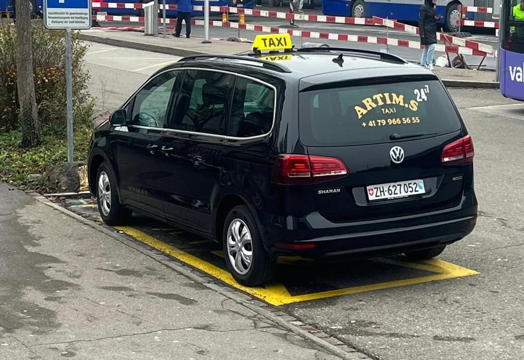 Schwarzer 7-Sitzer von Taxi Suli mit gelbem Taxischild und Artim-Schriftzug